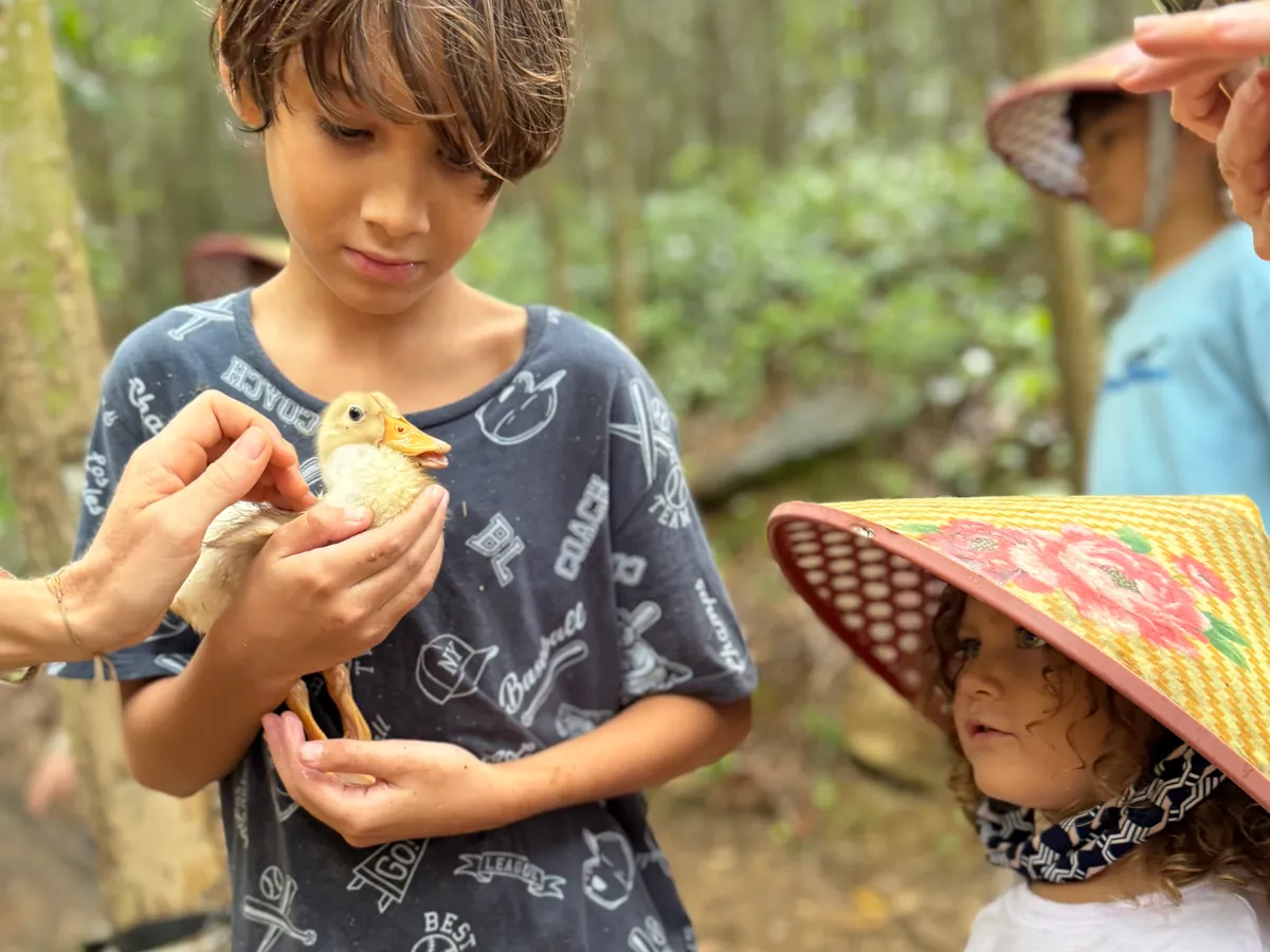 Tang Duck Farm Phong Nha Vietnam - Young boy gently holding a small duckling at Tang Duck Farm in Bong Lai Valley - World Travel Ambitions