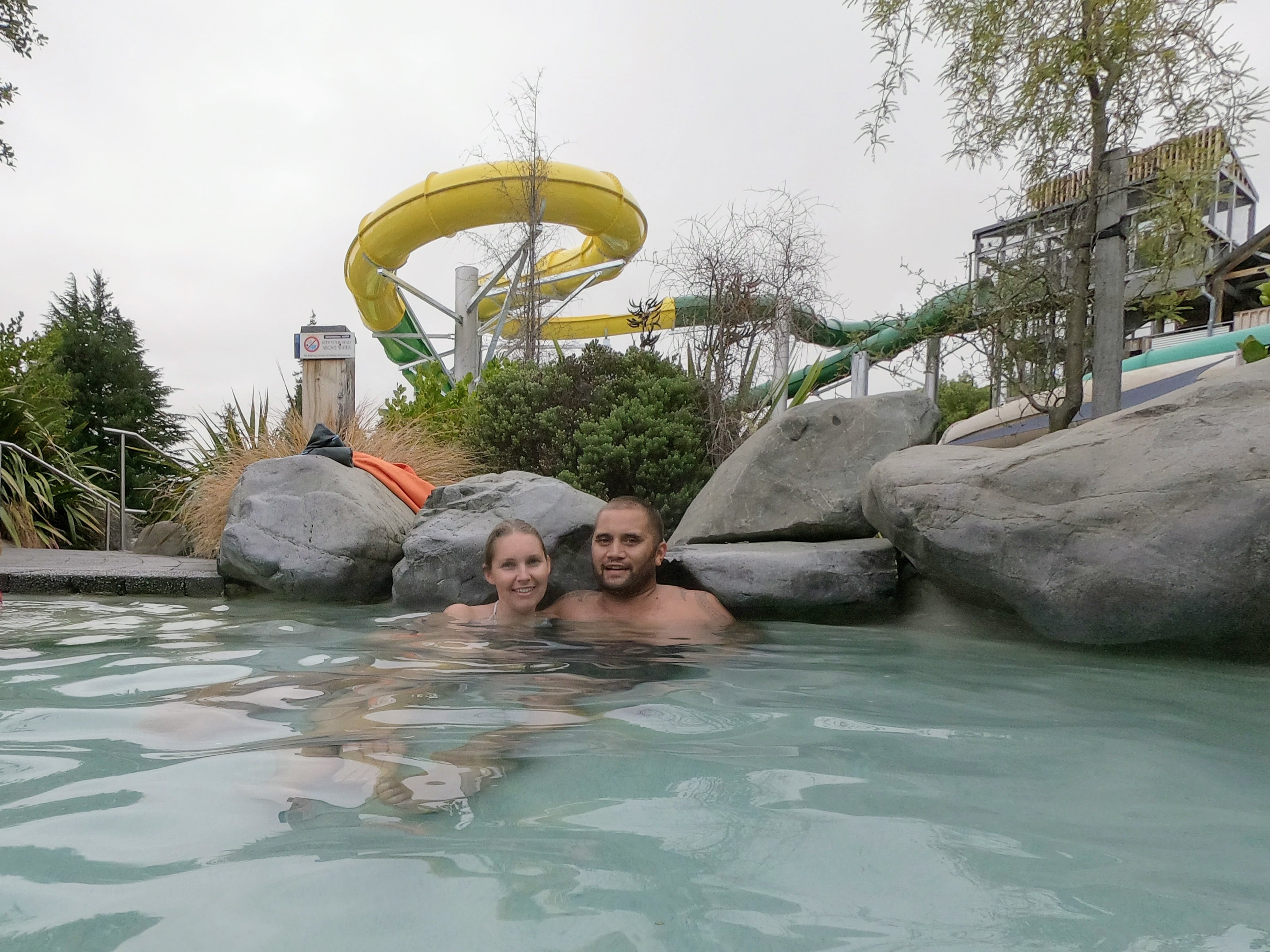 Couple enjoying hot springs at Hanmer Springs with water slides and natural rock pools in New Zealand