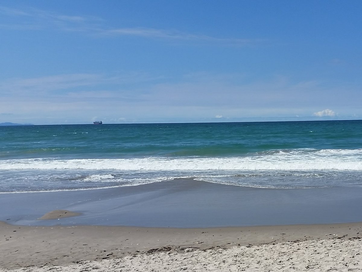 Beautiful Mount Maunganui beach scene with clear blue sky, turquoise ocean, and pristine sandy beach