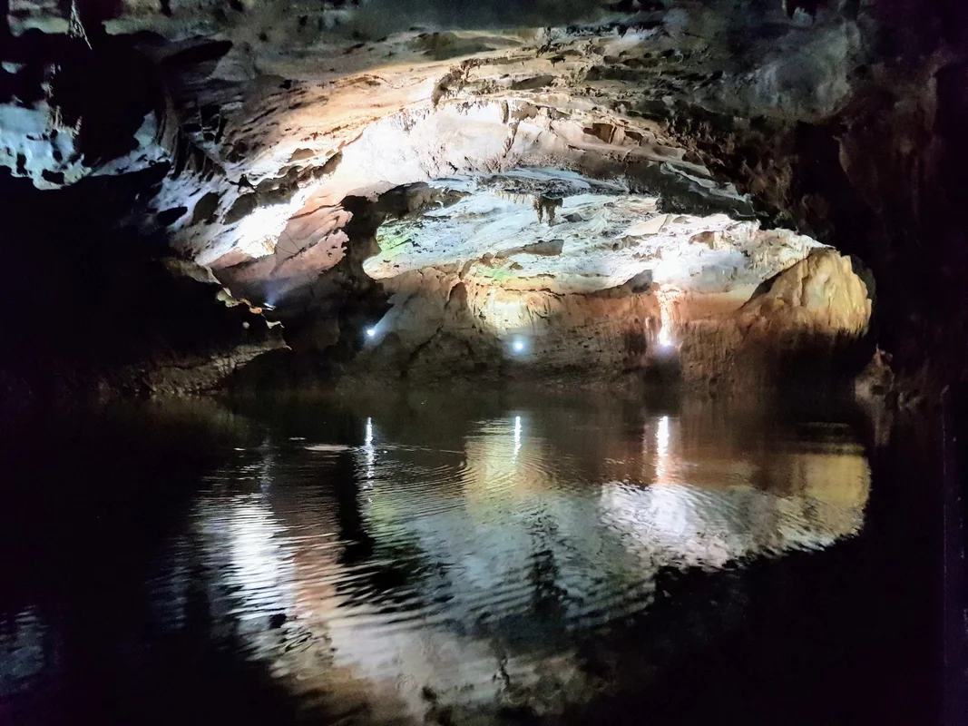Phong Nha Cave Vietnam - Stunning limestone cave entrance with crystal clear water reflecting the magnificent karst formations - World Travel Ambitions