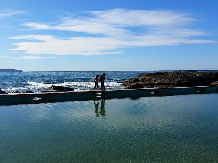 Whale Beach rock pool Sydney Northern Beaches - Kids exploring ocean pool edge with waves breaking across rocks for families